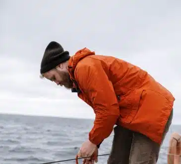 Man in Orange Jacket and Blue Denim Jeans Standing on Water