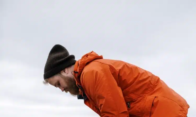 Man in Orange Jacket and Blue Denim Jeans Standing on Water