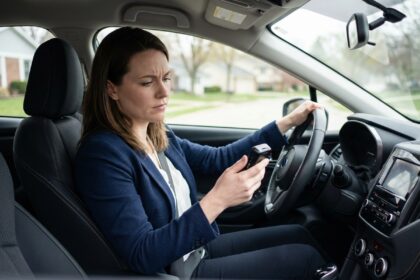 Jeune femme en voiture examinant un dispositif telematique