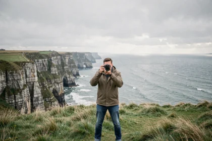 Photographe professionnel tenant un appareil photo face aux falaises normandes de la Manche